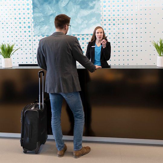 Hotel front desk staff in Kansas City using a two-way radio to assist a guest, supported by Commenco business security systems.
